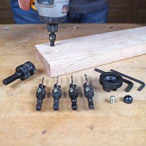 Woodworking countersink drill bit set with driver and accessories on workbench