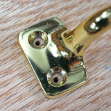 Brass hardware mounting plate with screw holes on finished wood surface