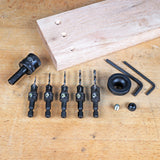 Woodworking countersink drill bit set, hex keys, and wooden board on workshop table