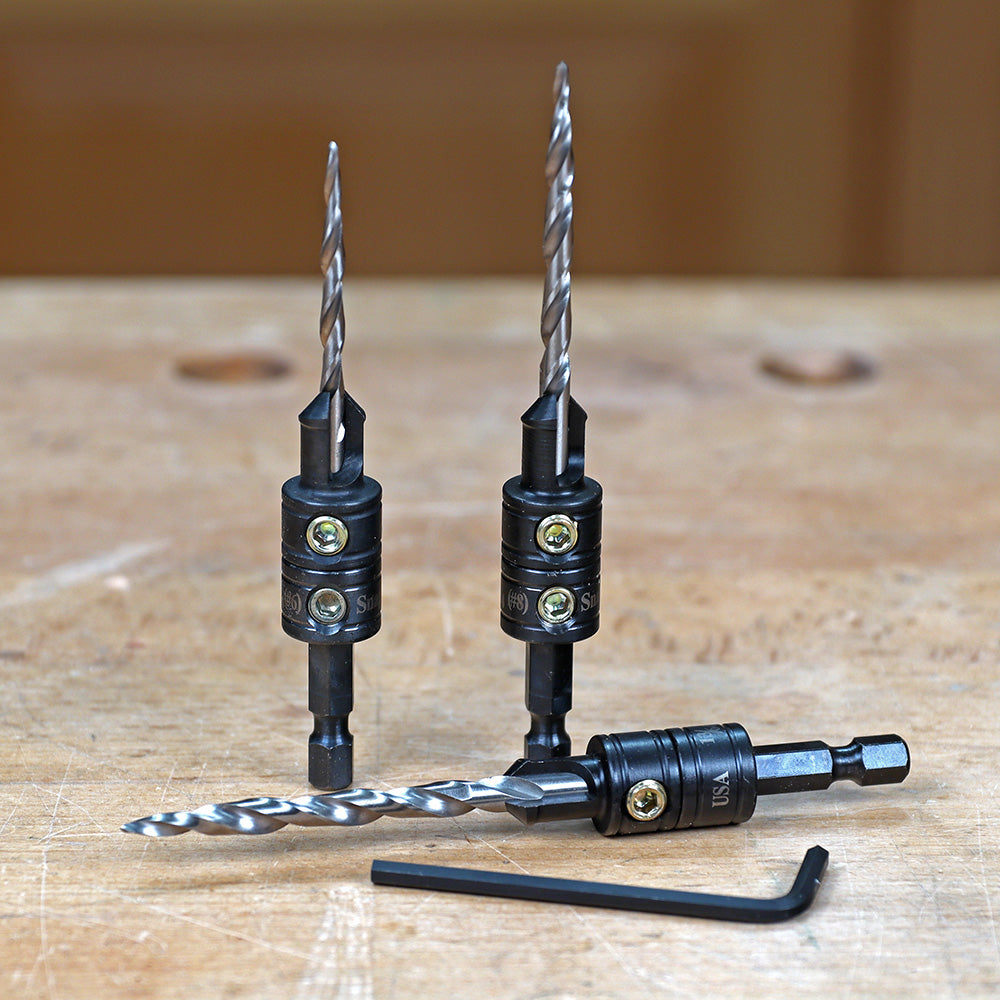 Set of woodworking drill bits with adjustable stops and hex key on a workbench
