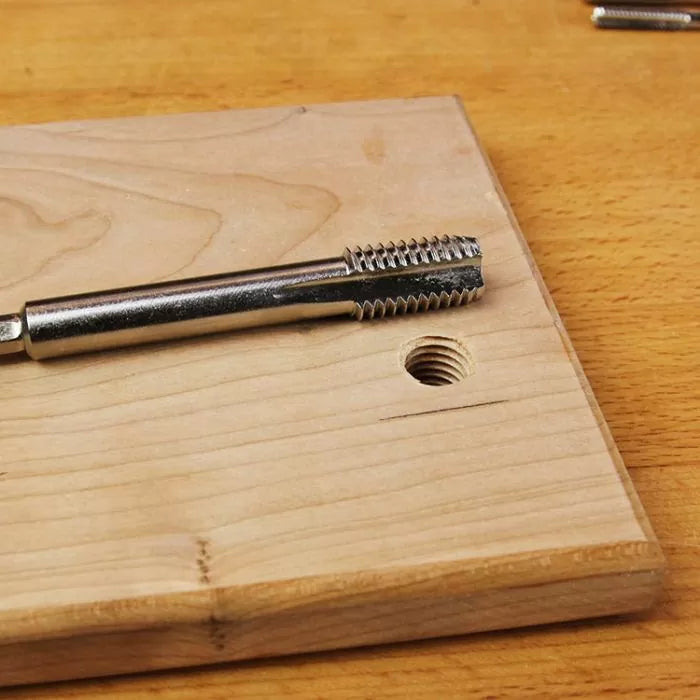 Metal thread tap tool on wood board with threaded hole, woodworking accessories