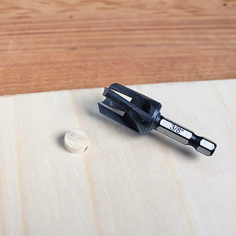 3/8 inch plug cutter drill bit on wood surface with a cut wood plug nearby for woodworking