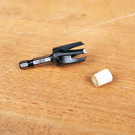 3/8 inch plug cutter drill bit and wood plug on workbench surface