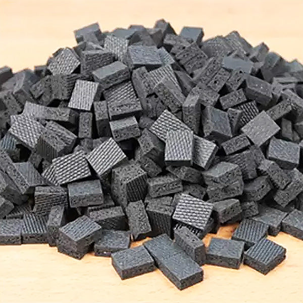 Pile of black rubber bench cookies for woodworking, textured anti-slip grip pads on wood surface