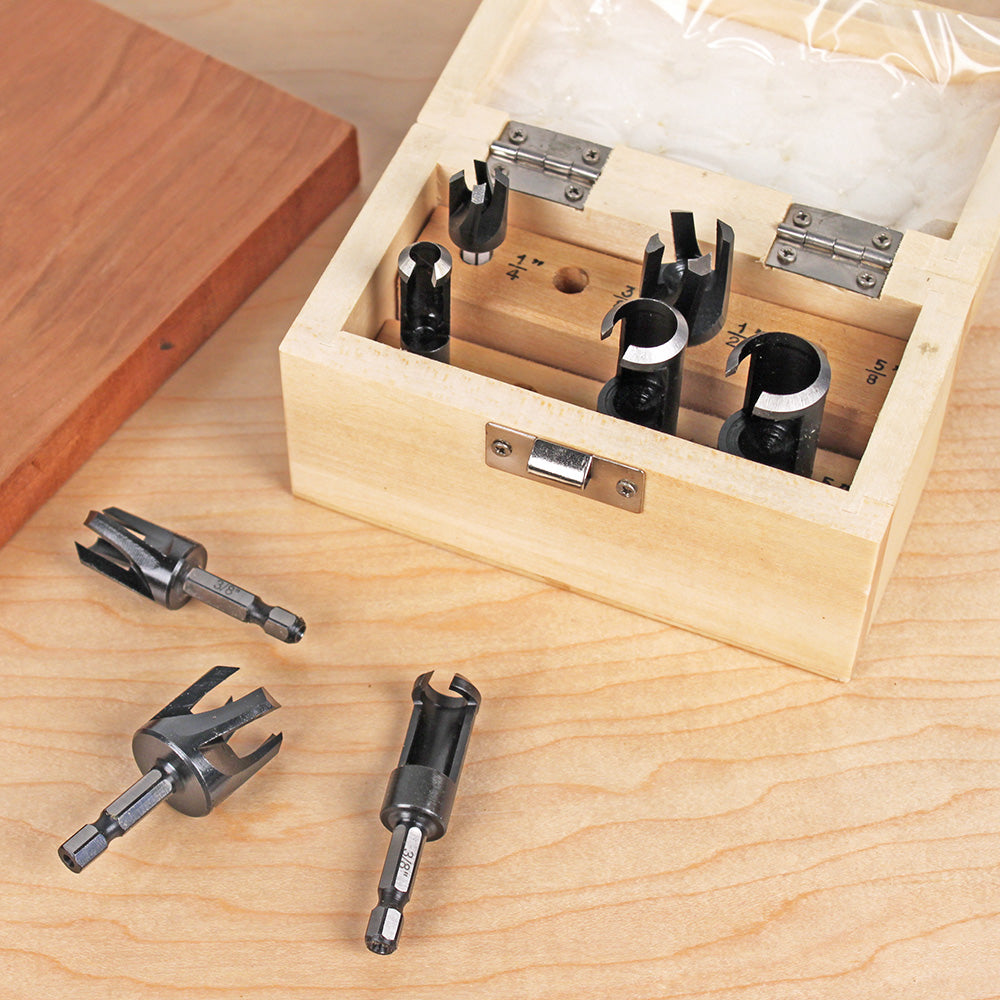 Woodworking plug cutter set in wooden box on workbench with four cutters displayed