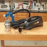 Wagner paint sprayer system with blue spray gun and hose on a woodworking bench
