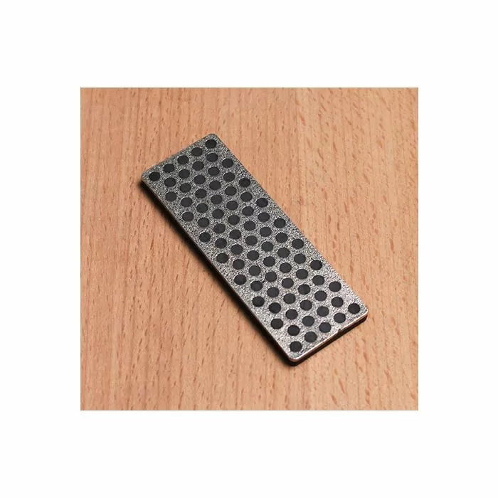 Diamond sharpening stone with perforated surface on wooden table, woodworking tool