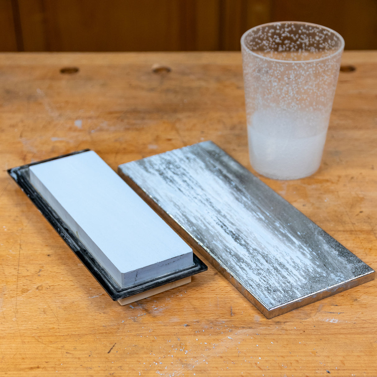 Sharpening stone, flattening plate, and water cup on woodworking bench