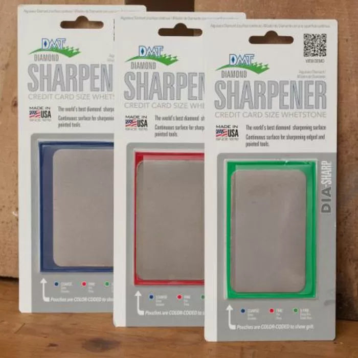 Set of three DMT diamond sharpeners in blue, red, and green packaging on wood surface
