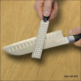 Hand sharpening kitchen knife with diamond sharpening stone on wood surface