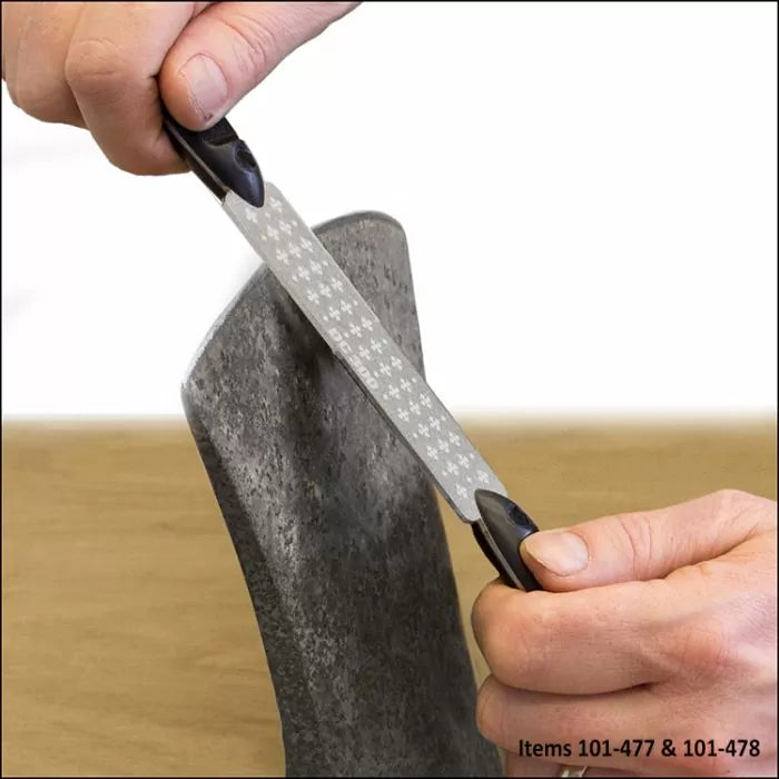 Sharpening an axe blade with a diamond sharpening file by hand on a wooden workbench.