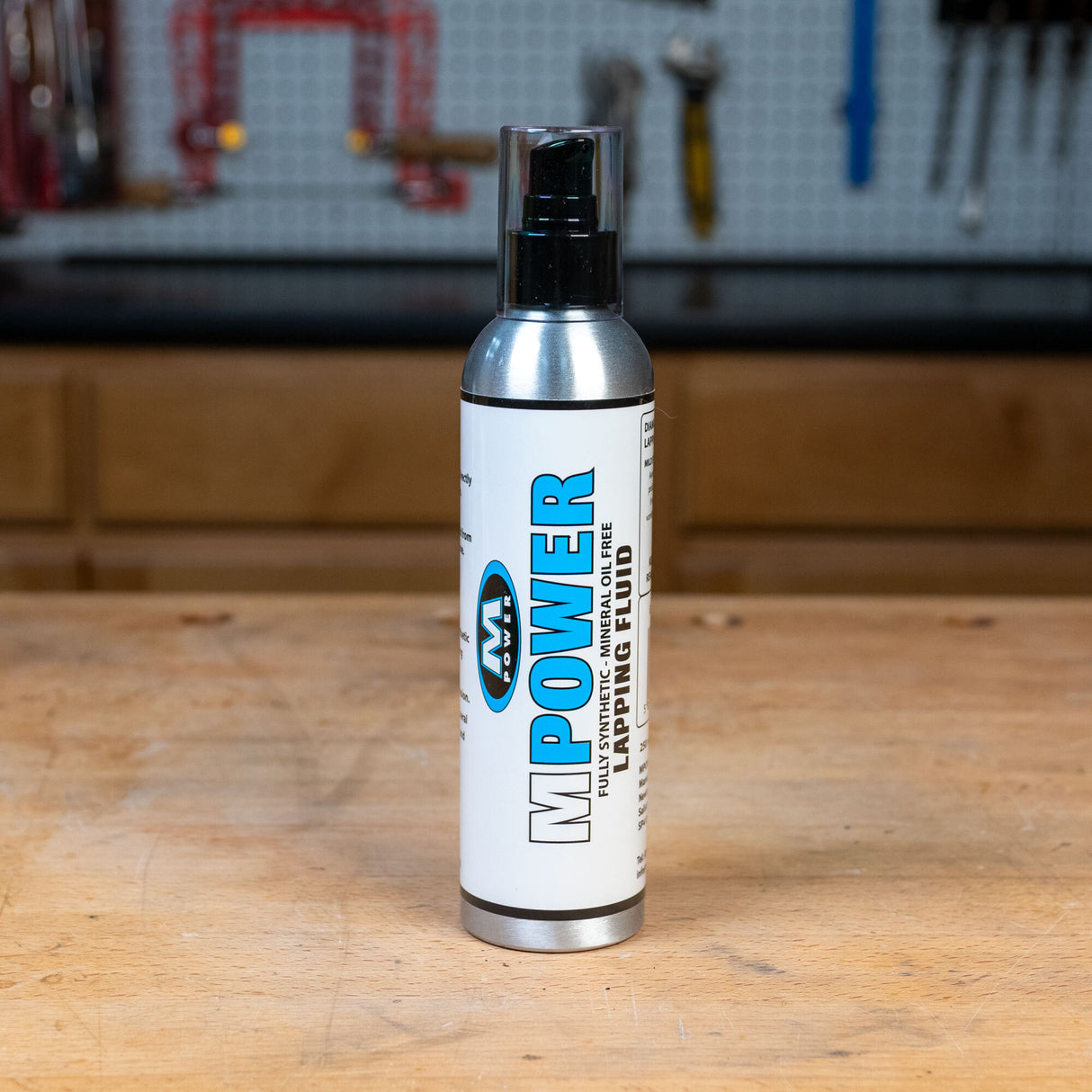 MPOWER lapping fluid bottle on a woodworking bench in a workshop setting