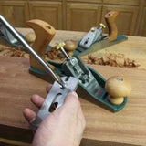 Hand adjusting a bench plane on a woodworking workbench with wood shavings