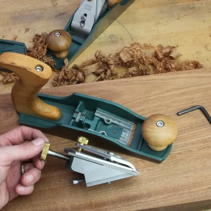 Frog mechanism for hand plane woodworking tool on wooden workbench with shavings