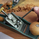 Hand adjusting woodworking hand plane frog screws with hex key on wooden workbench