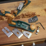 Disassembled bench hand plane with wood handle and metal parts on woodworking bench