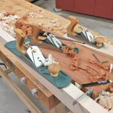 Woodworking hand planes with wood shavings on a workbench in a workshop setting