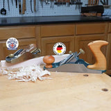 Two woodworking hand planes with wood shavings on a workbench in a workshop setting.