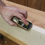 Hand using a block plane for woodworking edge breaking on a wooden board