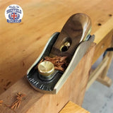 Hand plane tool smoothing wood edge on workbench, fine woodworking, shavings visible