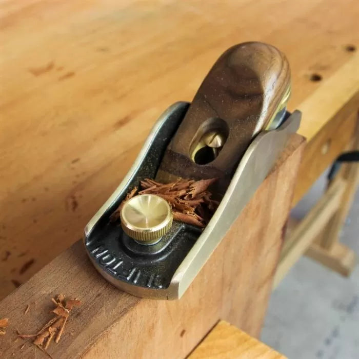 Block plane woodworking hand tool shaving wood on workbench