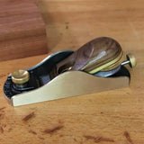 Low angle hand plane with brass and wood handle on a woodworking bench