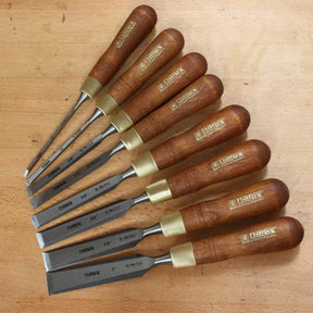 Set of seven woodworking chisels with wooden handles on a workbench