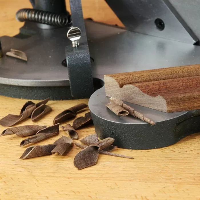 Woodworking jointer in use with wood shavings and freshly planed board on workbench
