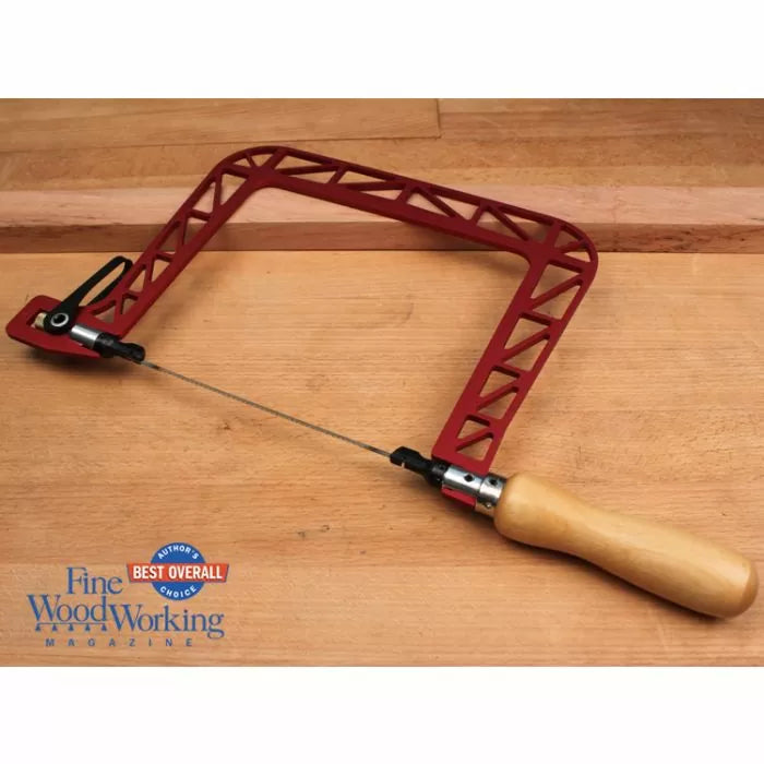 Red coping saw with wooden handle on wood surface, woodworking tool for precise cutting.