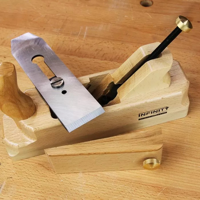 Wooden hand plane with metal blade and brass fittings on a workbench, woodworking tool