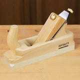 Wooden hand plane tool with beech handle on a workbench, ideal for woodworking projects.
