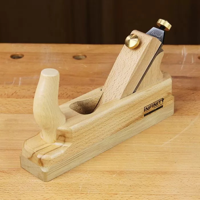 Wooden hand plane with brass fittings on a workbench, woodworking tool for smoothing wood.