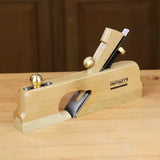 Wood jointer hand plane with brass fittings on a workbench for woodworking precision.