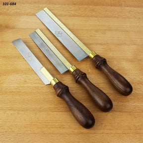 Set of three woodworking dovetail saws with brass backs and wooden handles on a wood surface