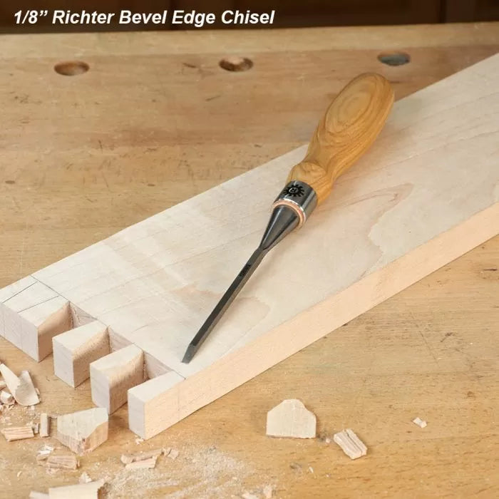 1/8 inch bevel edge chisel with wood handle on a workbench beside dovetail joints and wood shavings