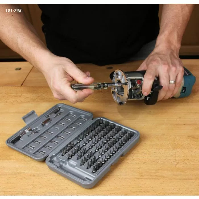 Person changing a router bit using screwdriver, with drill bit set on workbench