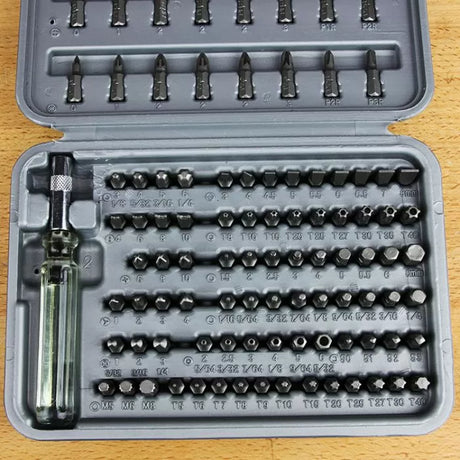 Precision screwdriver bit set with clear handle, assorted bits in plastic case on wood surface