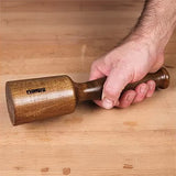Hand holding wooden woodworking mallet on workbench, ideal for precision joinery tasks