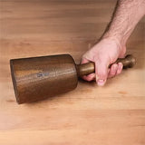 Woodworker holding a large wooden mallet on a workbench, woodworking hand tool