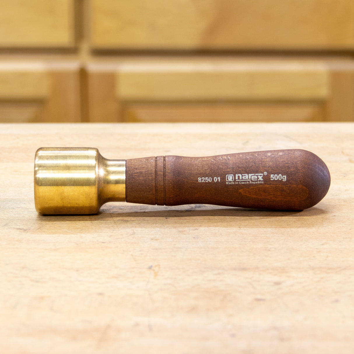 Narex brass mallet with wooden handle on a woodworking workbench