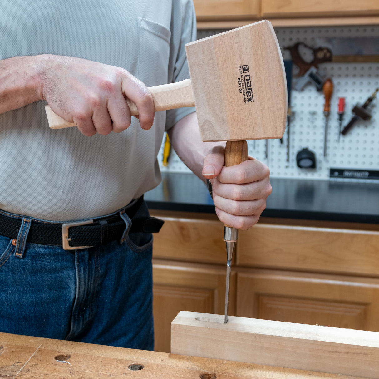 Woodworker using a Narex heavy bench mallet and chisel on a wood workbench in workshop