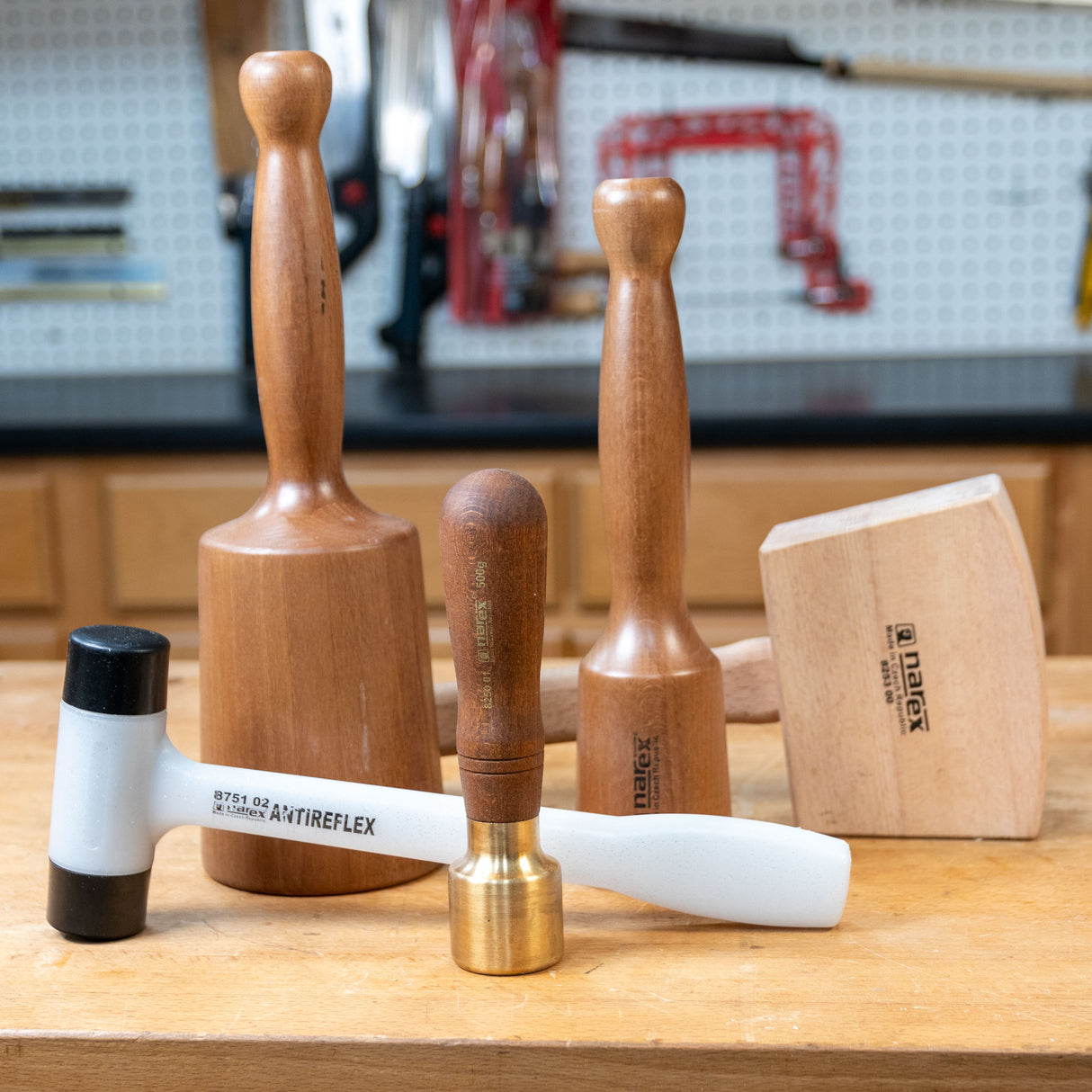 Woodworking mallet set with wood and brass handles on a workbench in a workshop.