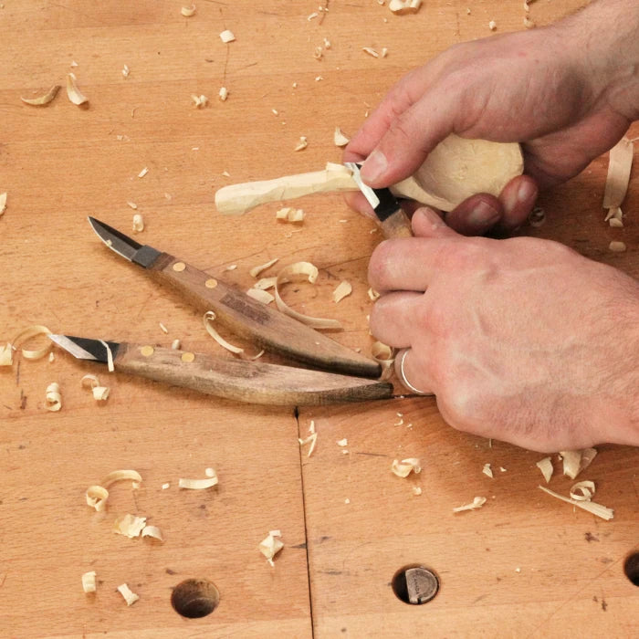 Hand carving wood with precision whittling knives on a woodworking bench