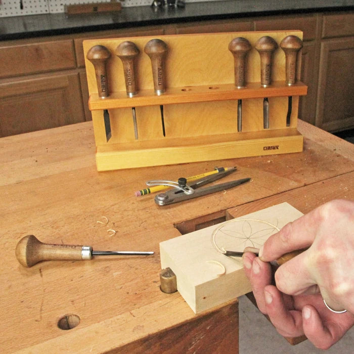 Woodcarving chisel set in wooden rack on workbench with hand carving geometric design in wood.