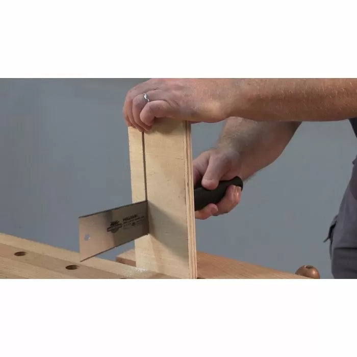 Person using a hand saw to cut plywood on a woodworking bench