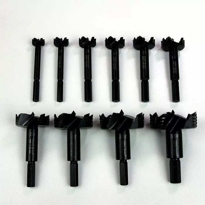 Set of ten black forstner drill bits for woodworking on white background.