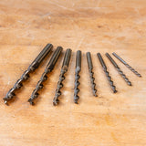 Metric brad point drill bit set arranged on a wooden surface for woodworking projects