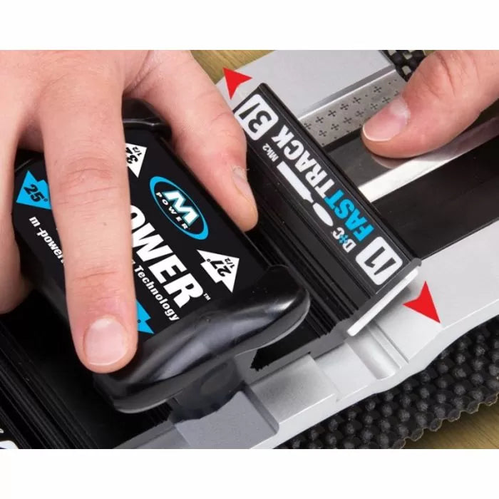 Manual sharpening system in use, hands holding blade and miter guide on workbench