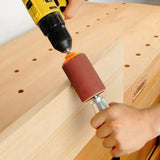 Hand using a drill with sanding drum attachment on wooden board at workbench