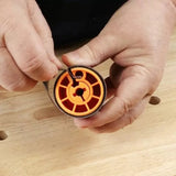 Hand adjusting orange woodworking router bit collet on a workbench
